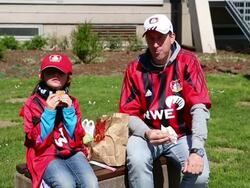 Mid shot of Leverkusen fan with daughter eating Stock Footage