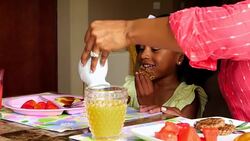 MS Smiling young girl watching mother pour syrup over pancakes at breakfast Stock Footage