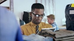 Modern clothing store employee works on tablet and checks price tags of stock Stock Footage