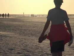 WS View of people walking on sea coast and sea sand flying by wind during sunset, North Sea North Frisia, / St. Peter Ording, Schleswig Holstein, Germany Stock Footage