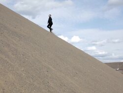 MS Young businessman dressed in  black suit walking on  sand dune in  rural area / Maple Grove, Minnesota, United States Stock Footage