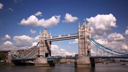 Clouds drift over the Tower Bridge where traffic crosses the Thames River. Stock Footage