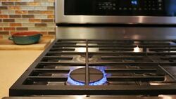 Woman's hand placing stainless steel cooking pot on natural gas stove in home kitchen Stock Footage