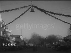 1952: CHRISTMAS IN ELKHORN: VS Large bell & garlands (wreaths) hanging over Main Street in Elkhorn city, parked cars, shops, & pedestrians on streets lower frame. Wisconsin, WI, Xmas, Winter, holidays Instructional Video