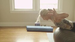 A mature woman uses an exercise ball to do sit-ups in her home gym. Stock Footage