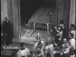 1949: CHRISTMAS EVE 'HOLY YEAR' CEREMONY: Procession of people standing behind pontiff as Portia Santa (The Holy Door) is lowered, like gate, opened, Pope Pius XII walking through doorway w/ Swiss Guards making others wait. Instructional Video