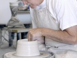 MS TD senior potter sitting at spinning pottery wheel shaping wet clay with his hands / Palm Springs, California, USA Stock Footage