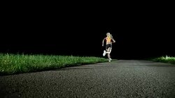 SLO MO PAN Female marathon runner running at night Stock Footage