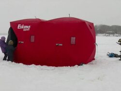 WS Girl helping brother inside ice fishing house during winter / Minneapolis, Minnesota, USA Stock Footage