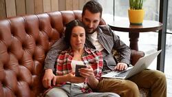 young couple sitting on sofa and using gadgets Stock Footage