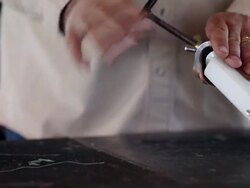 PAN TU TD boot maker standing at counter in workshop removing vamp of cowboy boots from stretcher Stock Footage