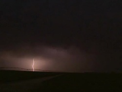 Bright single bolt of forked cloud to ground lightning under severe thunderstorm at night. Stock Footage
