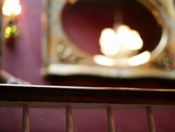 Man walking along hotel corridor with fedora on banister Stock Footage