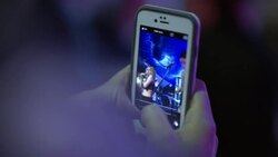 Fan takes photos with smartphone of rock band performing on stage at music festival Stock Footage