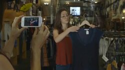 girl being filmed by smart phone holding up dress for fashion blog Stock Footage