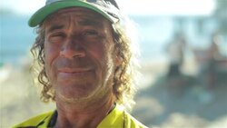 Old fisherman in Brazilian team colors smiles for camera on Copacabana Beach Stock Footage