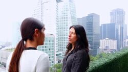 MS SWISH PAN Female business executives standing in discussion on office terrace overlooking city Stock Footage