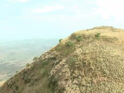 Wide Shot - Two Maasai warriors walk through the shrubs on a rounded mountain peak / Kenya Stock Footage
