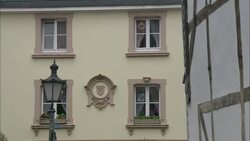 A pale yellow building bears a crest between its four windows. Stock Footage