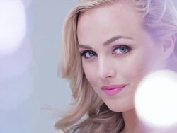 CU dolly LR  beautiful young woman seen through bokeh looking to camera hair blowing in wind Stock Footage