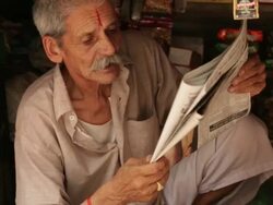 Senior man reading newspaper in a shop, Rishikesh, Uttarakhand, India Stock Footage