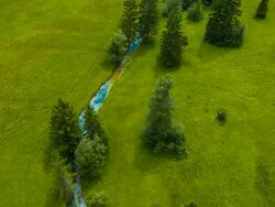 Aerial flight over blue stream flowing through meadows Stock Footage
