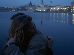 Medium shot man and woman embracing on the bank of the Charles River / Prague Stock Footage