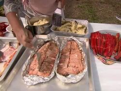 "Pan right to left of various salmon dishes on table with women making final preparations. Metlakatla, Annette Island, Alexander Archipelago, Alaska." Stock Footage