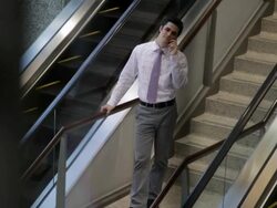 MS Young businessman talking on cellphone in middle of two sets of escalators in ofice building / Minneapolis, Minnesota, United States Stock Footage