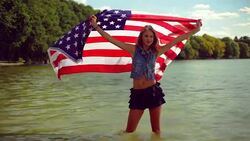 Blond girl waving American flag in the lake. Stock Footage