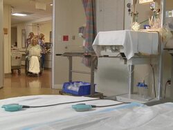 Nurse pushing a pregnant woman in a wheelchair into an operating room Stock Footage