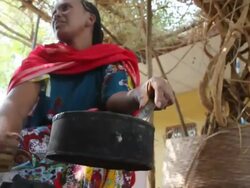 Ethiopian woman fanning fire to roast coffee grains Stock Footage