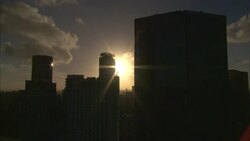 A sunburst beams between silhouetted skyscrapers in Sydney, Australia. Stock Footage