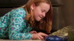 Cautious young girl looks over her shoulder before shaking presents beneath Christmas tree Stock Footage