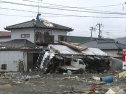 Destruction caused by tsunami after magnitude 9 Tohoku earthquake, north east Japan, March 2011. Truck lies on side of smashed house Stock Footage