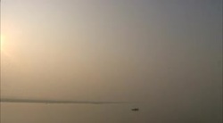 A lone boat floats on the distant horizon of the hazy Ganges River. Stock Footage