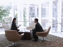  PAN Business associates sitting in corner of lobby discussing documents / Seattle, Washington, United States Stock Footage