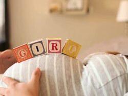 A pregnant women using blocks to spell the word GIRL on her stomach. Stock Footage
