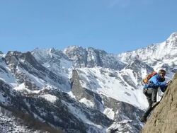 Pan to young climber scaling cliff, father belays Stock Footage