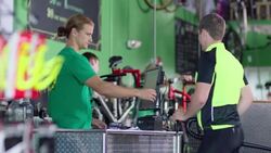 Bike shop employee swipes credit card and returns it to cyclist customer at sales counter Stock Footage