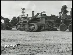1942: UNITED STATES WAR EFFORT IN MELANESIA: VS U.S. workers driving tractor tanks pulling construction parts on sand, workers unboxing incomplete fighter airplane fuselage, tractor pulling airplane. World War II, WWII, war production, assembly Instructional Video