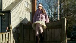 Michaela Butin sits on a fence on a windy autumn day in Boston, Massachusetts. Stock Footage
