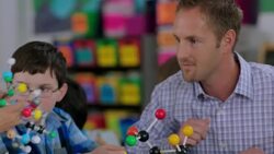 Teacher helps students assemble molecule model Stock Footage