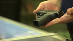Gun dealer holding Smith and Wesson pistol News Clip