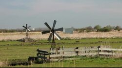 Traditional wind pumps used to help drain low lying polder land reclaimed from the sea on the outskirts of Amsterdam, Netherlands Stock Footage