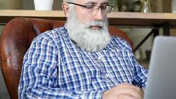 Adult senior bearded man sitting with a laptop Stock Footage