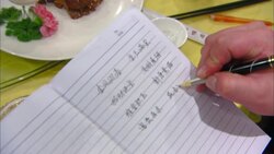 A hand writes Chinese characters onto a notebook near a food display at the Panda Display Center in China. Stock Footage