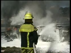 MCU Fire fighter hosing down burning tanker truck with foam Stock Footage