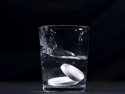 CU SLO MO Tablets falling into a glass of water against / Vieux Pont, Normandy, France  Stock Footage