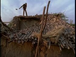 MS Low angle, Gujarat, Indian man on roof of ruined house, after earthquake, Gujarat, India Stock Footage